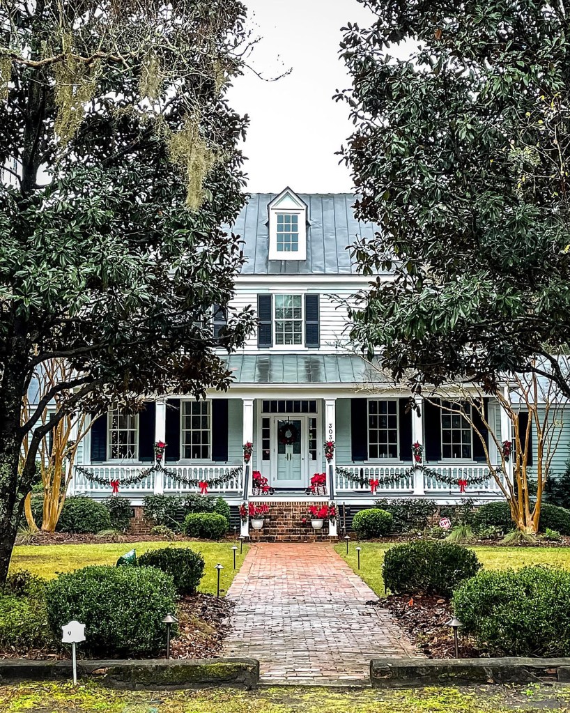 A brick and tree-lined driveway home in Summerville, known as 'Charleston's little sister', famous for its blooming flowers and historic charm.